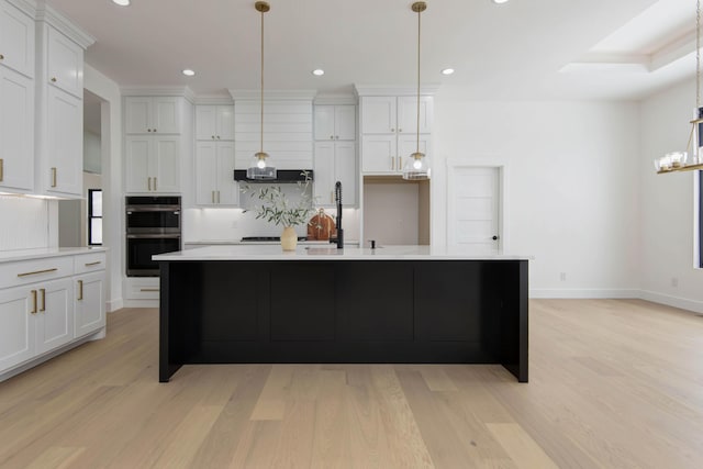 kitchen featuring double oven, white cabinets, light countertops, and light wood-style floors