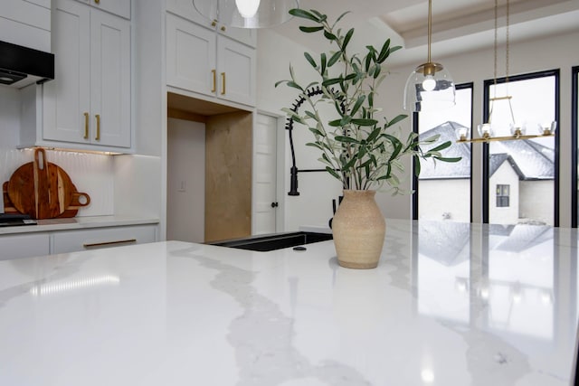 kitchen with white cabinets, decorative light fixtures, and exhaust hood