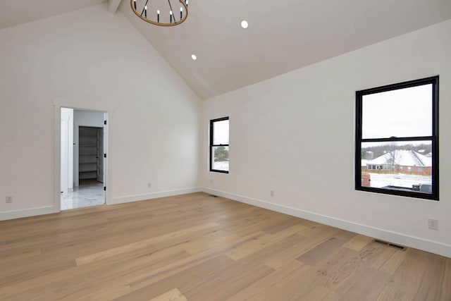 unfurnished room featuring high vaulted ceiling, light wood finished floors, visible vents, and an inviting chandelier