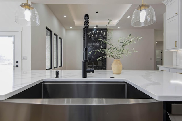 kitchen featuring light stone counters, a tray ceiling, decorative light fixtures, and recessed lighting