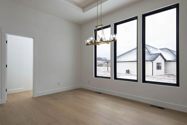 spare room featuring light wood-style floors, baseboards, visible vents, and a notable chandelier