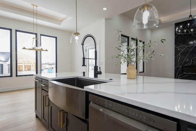 kitchen featuring dishwasher, hanging light fixtures, a tray ceiling, and a sink