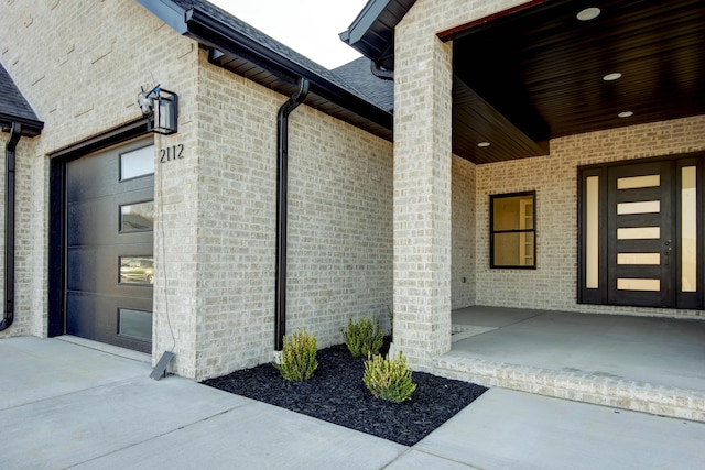 entrance to property featuring brick siding and a garage