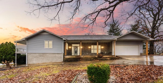 ranch-style house with brick siding, a porch, concrete driveway, and an attached garage