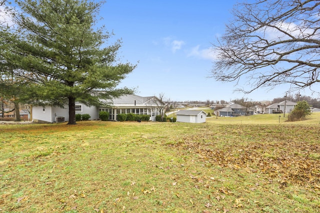 view of yard with an outdoor structure, central air condition unit, a shed, and a sunroom