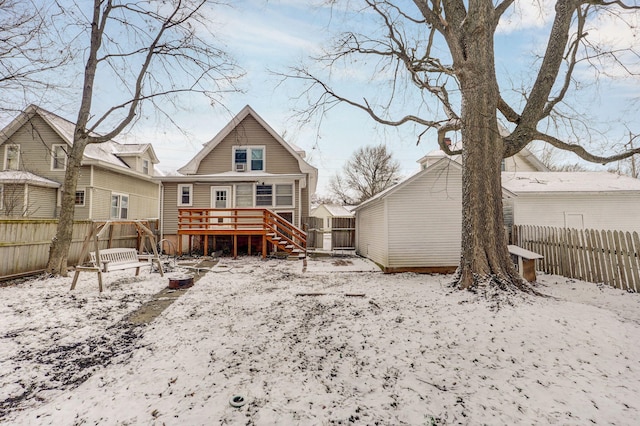 snow covered back of property featuring fence and a wooden deck