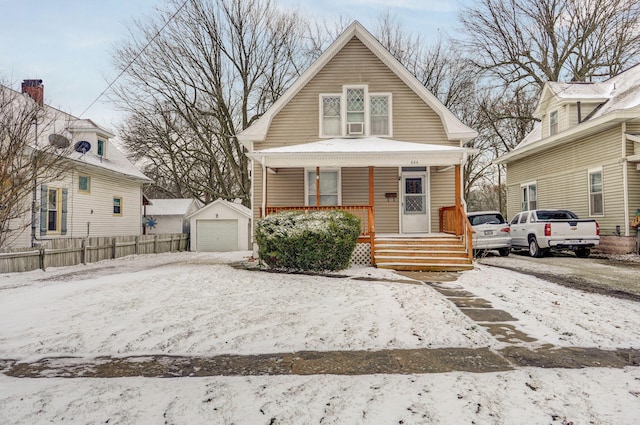 bungalow-style home featuring a detached garage, fence, a porch, and an outbuilding