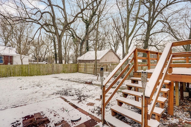 snowy yard with stairs and a fenced backyard