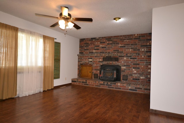 unfurnished living room with a textured ceiling, wood finished floors, baseboards, ceiling fan, and a wood stove