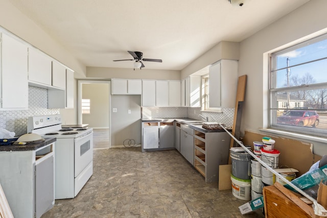 kitchen featuring white electric range, a wealth of natural light, and white cabinetry