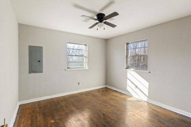 spare room featuring electric panel, visible vents, baseboards, ceiling fan, and wood finished floors