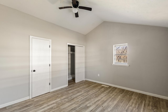 unfurnished bedroom with visible vents, baseboards, lofted ceiling, light wood-style flooring, and ceiling fan