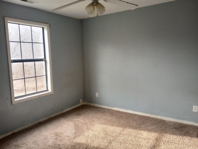 carpeted spare room featuring baseboards, visible vents, and a ceiling fan