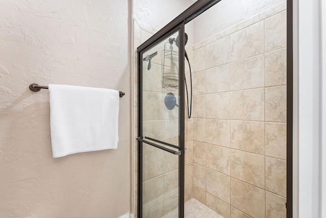 full bath featuring a shower stall and a textured wall