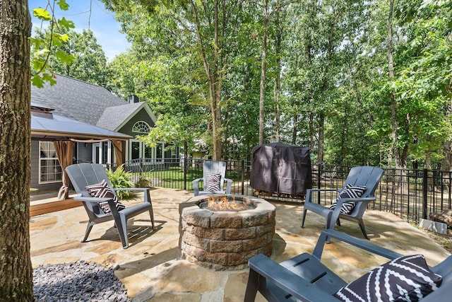 view of patio with area for grilling, fence, a fire pit, and a gazebo