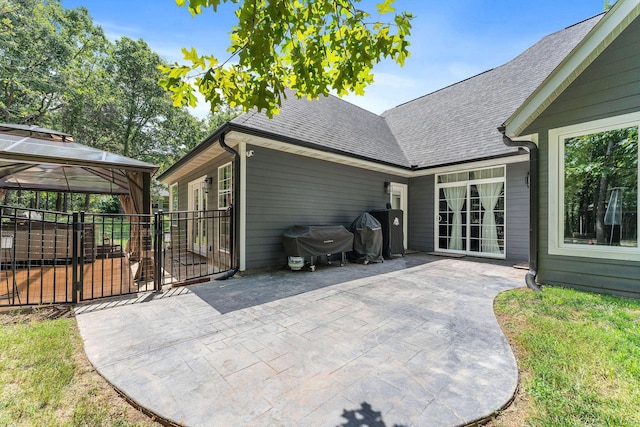 view of side of home featuring a shingled roof and a patio