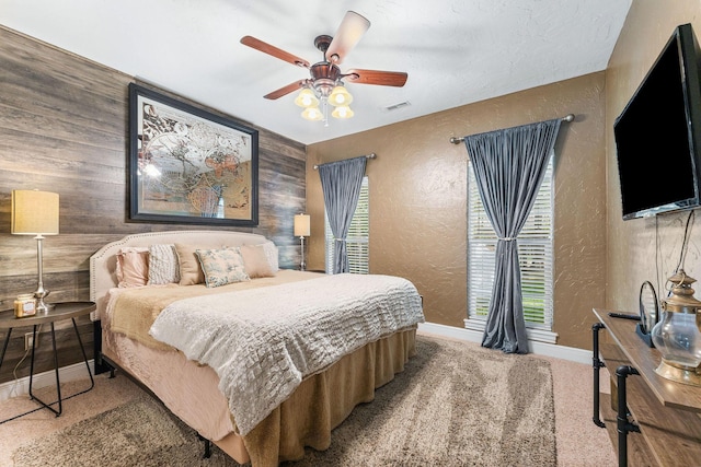 bedroom featuring carpet, visible vents, baseboards, and a textured wall