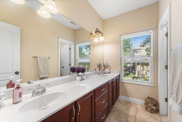 bathroom with double vanity, baseboards, visible vents, and a sink