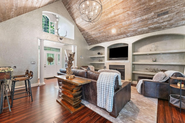 living room featuring built in features, a fireplace, visible vents, hardwood / wood-style floors, and ornate columns