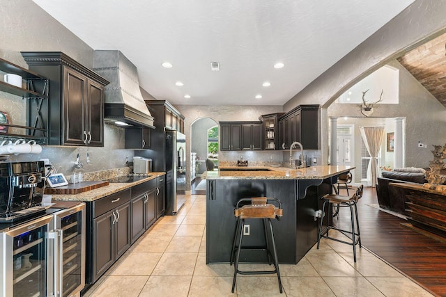 kitchen featuring light stone countertops, custom range hood, arched walkways, and open shelves