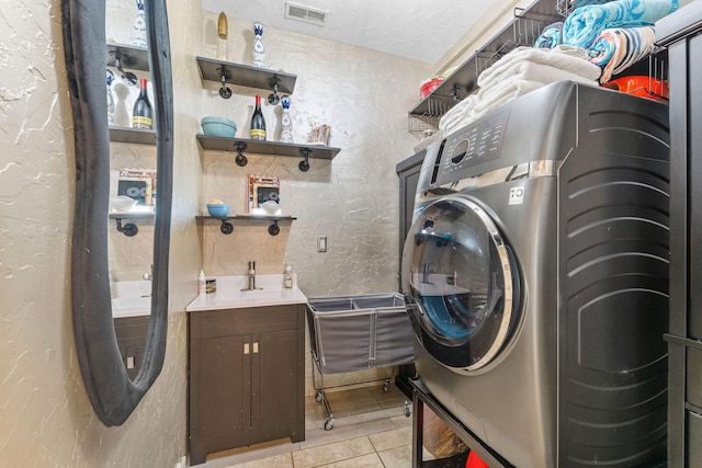 washroom featuring washer / clothes dryer, visible vents, a textured wall, and light tile patterned floors