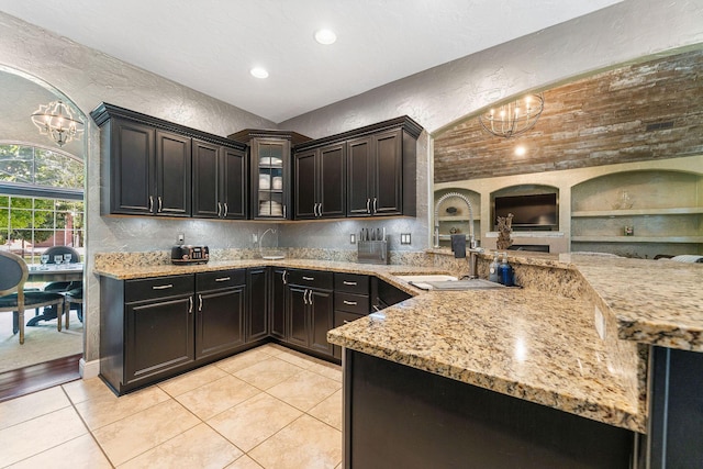 kitchen featuring a textured wall, light stone counters, and an inviting chandelier