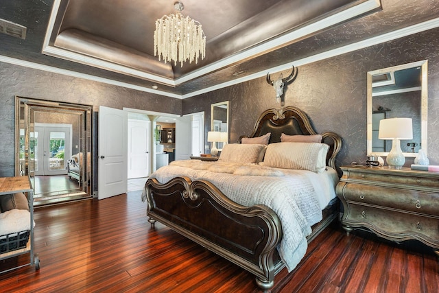 bedroom featuring hardwood / wood-style flooring, a notable chandelier, visible vents, ornamental molding, and a tray ceiling