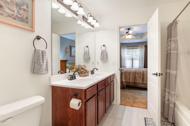 ensuite bathroom featuring ensuite bathroom, double vanity, a sink, and toilet