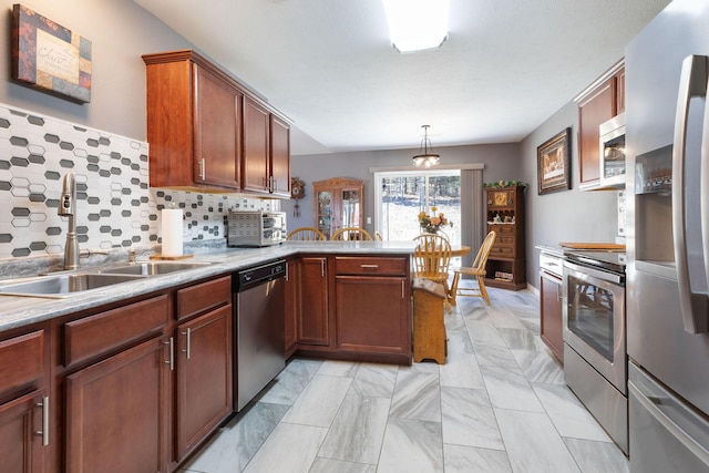 kitchen with tasteful backsplash, light countertops, appliances with stainless steel finishes, a sink, and a peninsula