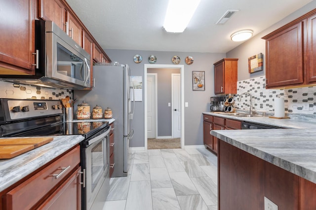 kitchen with stainless steel appliances, a sink, visible vents, light countertops, and tasteful backsplash