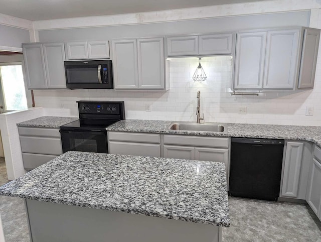 kitchen with a sink, gray cabinets, decorative backsplash, light stone countertops, and black appliances