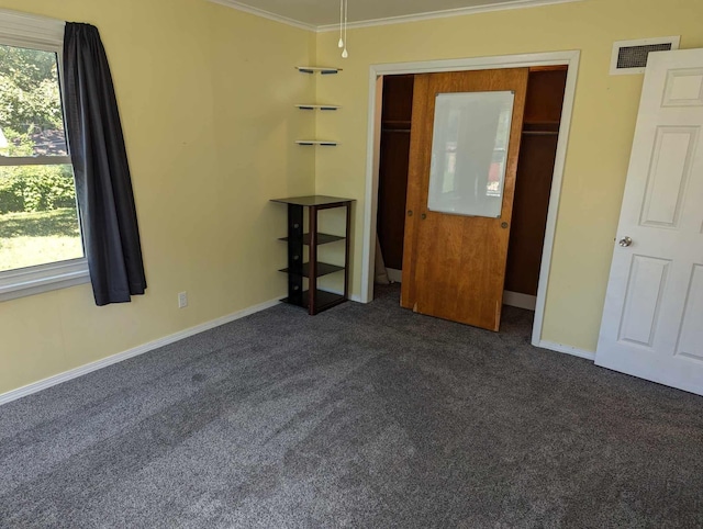 unfurnished bedroom with baseboards, visible vents, dark carpet, and ornamental molding