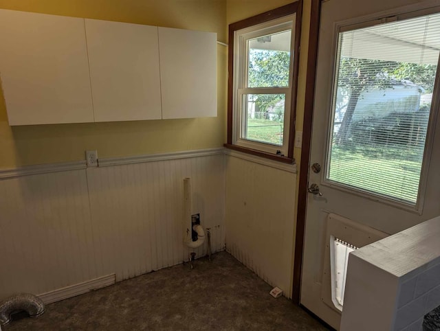 laundry room with dark colored carpet, a wainscoted wall, and wooden walls