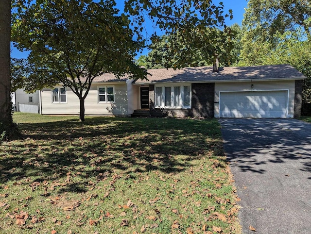 single story home featuring a garage, brick siding, a front lawn, and aphalt driveway