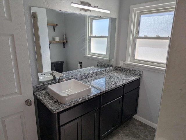 bathroom featuring baseboards, a wealth of natural light, and vanity