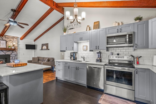 kitchen featuring dark wood-style floors, stainless steel appliances, gray cabinetry, open floor plan, and a sink