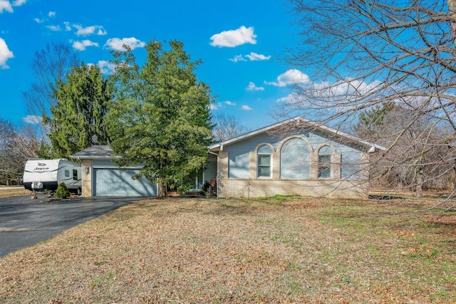 view of front of property featuring a garage, driveway, brick siding, and a front yard