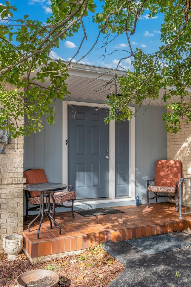 doorway to property featuring covered porch and brick siding