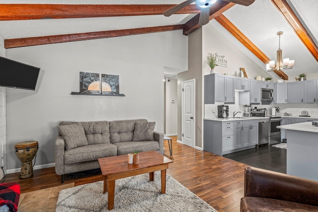 living room with baseboards, dark wood-type flooring, a textured ceiling, beam ceiling, and ceiling fan with notable chandelier