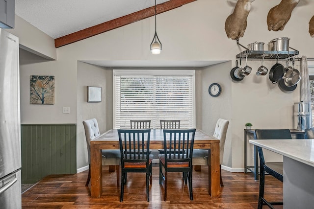 dining room featuring vaulted ceiling with beams, a wainscoted wall, dark wood finished floors, and a textured ceiling