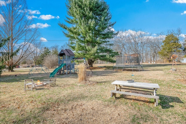 community playground with a trampoline, a lawn, and a fire pit