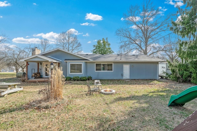 back of property with an outdoor fire pit, a chimney, and a yard