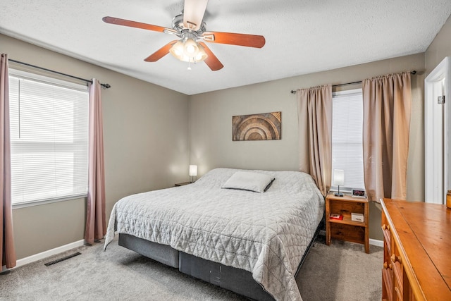 bedroom with carpet floors, visible vents, a ceiling fan, a textured ceiling, and baseboards