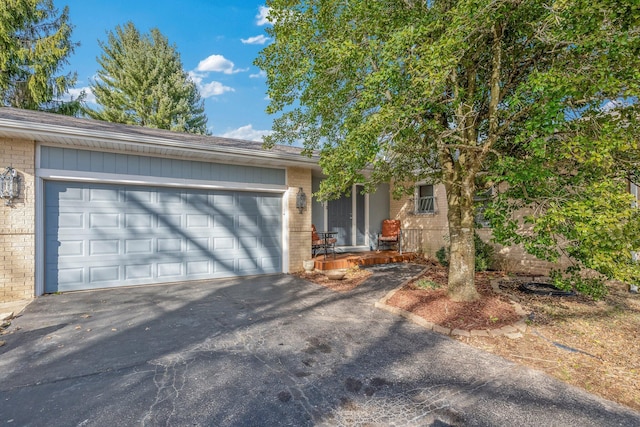 ranch-style house with aphalt driveway, brick siding, and an attached garage