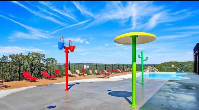 view of play area with fence, a community pool, and a patio