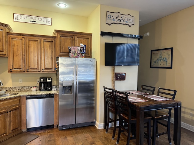 kitchen featuring appliances with stainless steel finishes, dark wood-style flooring, and brown cabinets