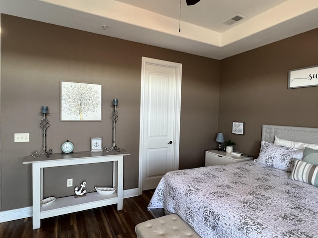 bedroom featuring dark wood-style floors, baseboards, visible vents, and a raised ceiling