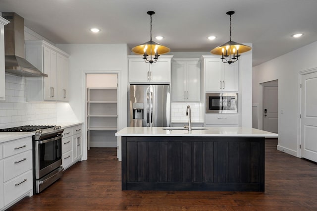 kitchen with stainless steel appliances, dark wood finished floors, a sink, and wall chimney exhaust hood