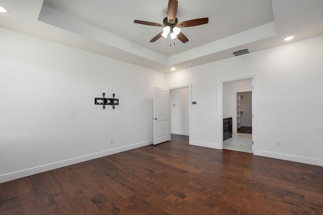 interior space with a tray ceiling, visible vents, baseboards, and wood finished floors