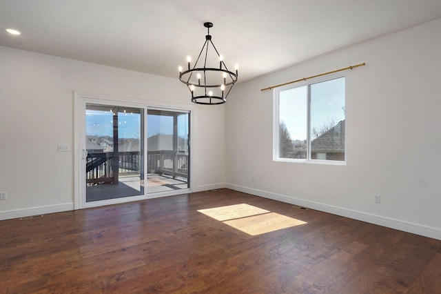 empty room featuring a wealth of natural light, hardwood / wood-style floors, and an inviting chandelier